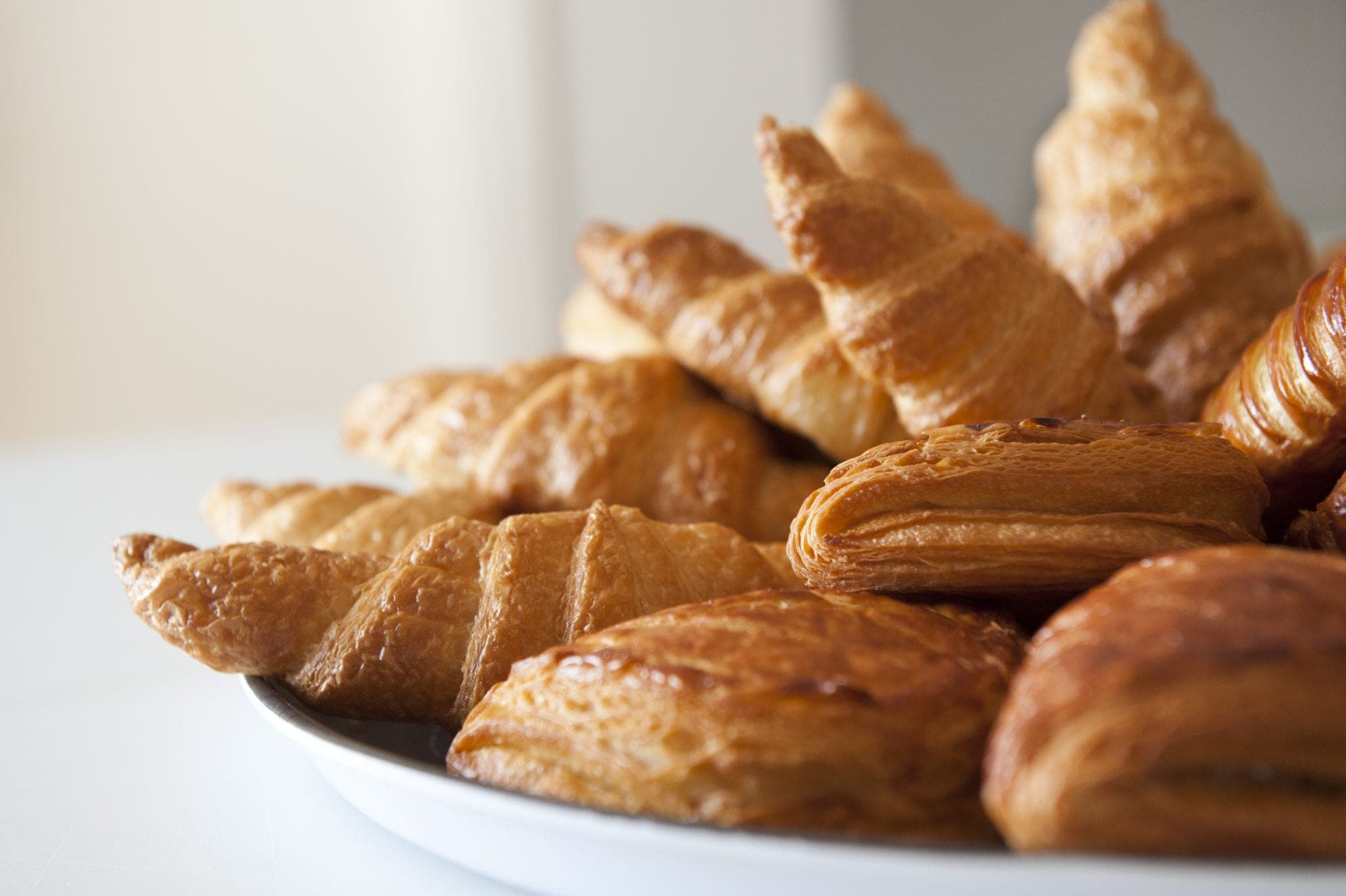 A plate piled with golden croissants and pastries
