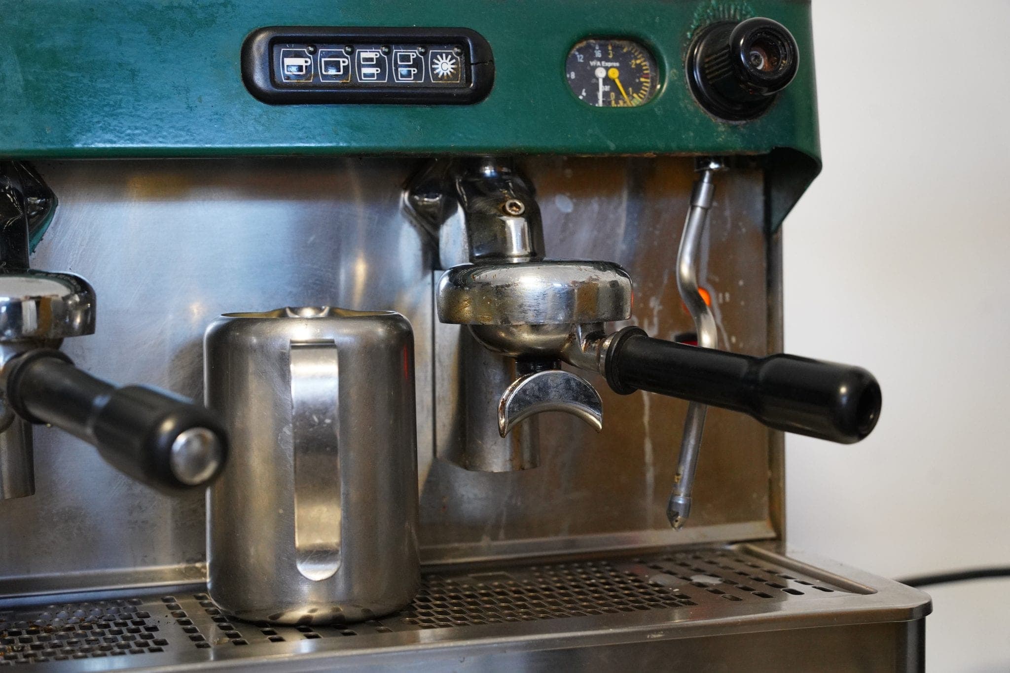 Close-up of a polished two-group espresso machine with a steel milk jug