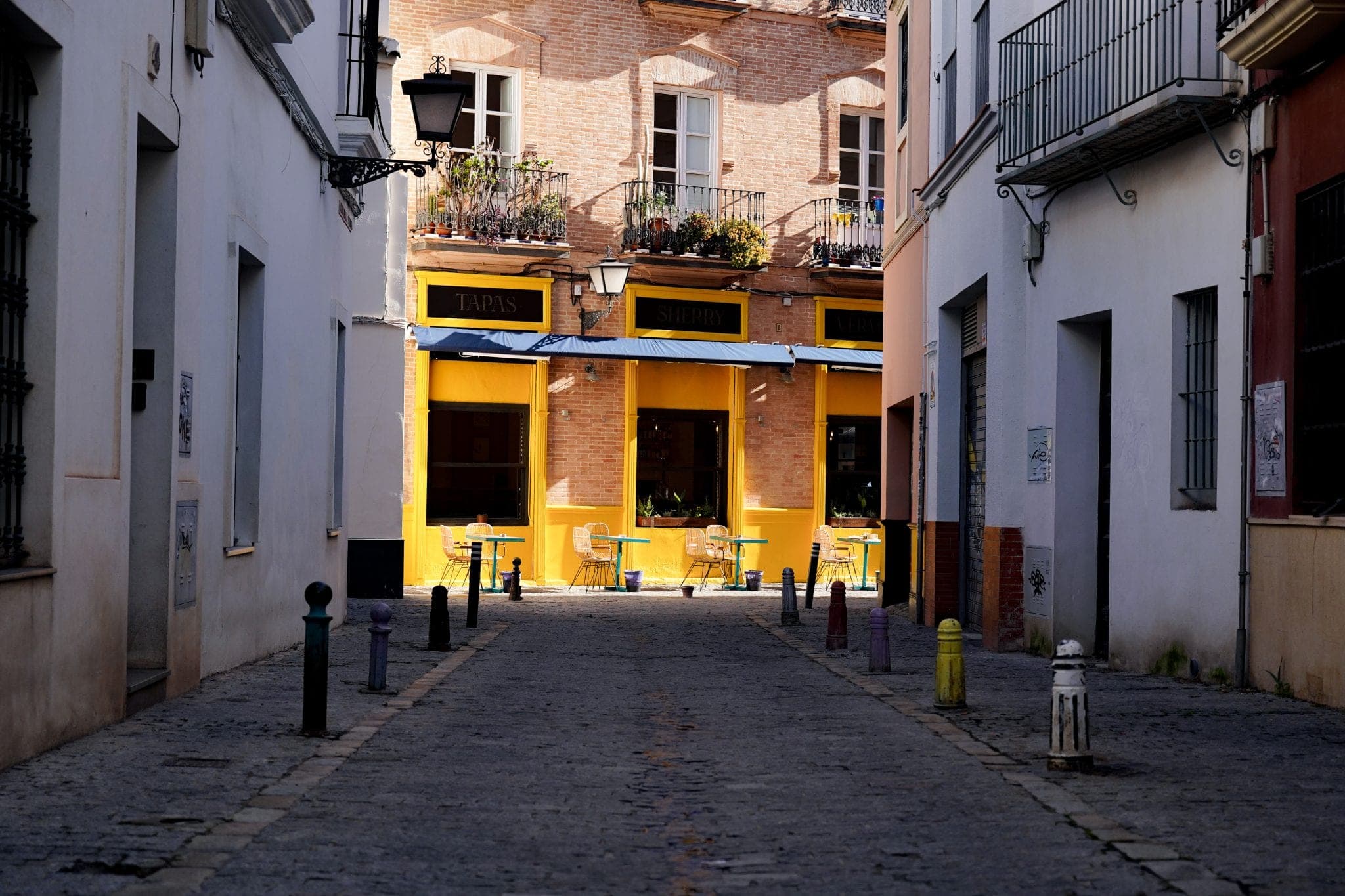 A narrow cobbled street leading to a café with a yellow façade
